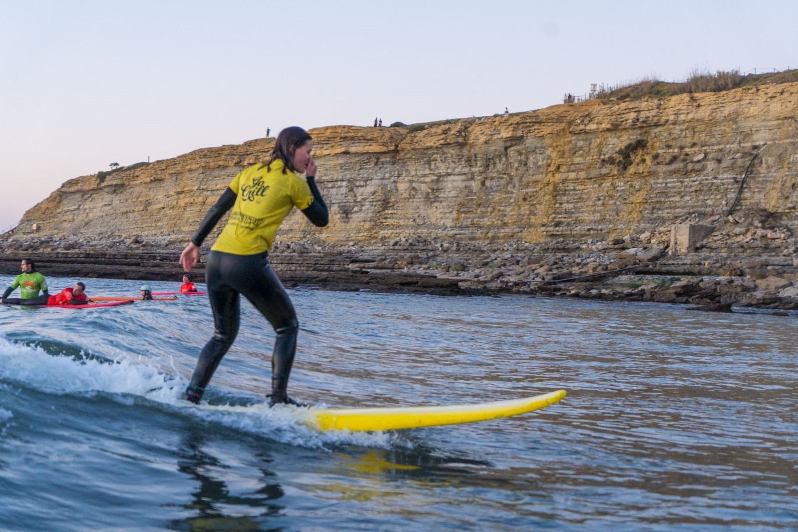 A beginner surfer smiling with one hand over her mouth